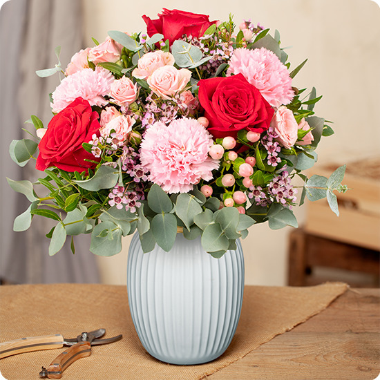 Bouquet Déclaration avec roses rouges, carnations rose tendre, roses branchues, et eucalyptus, vu sur le comparateur bloomyrama