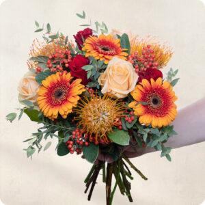 Bouquet Safran aux tons chauds avec gerberas roses baies et leucospermum 123fleurs vu sur le comparateur bloomyrama
